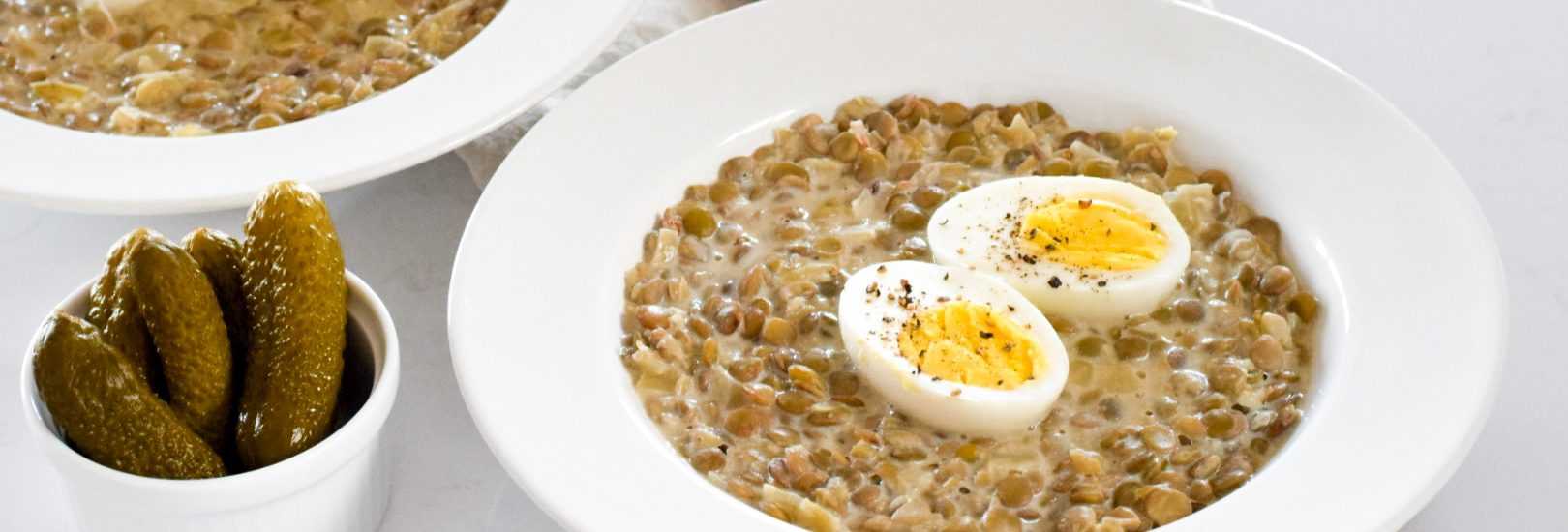 Čočka se zakysanou smetanou, vajíčkem a kyselým okurkem.